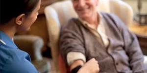 old man in chair with nurse