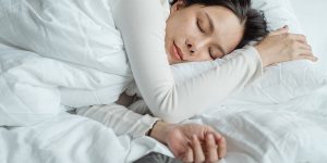 a woman sleeping with white covers